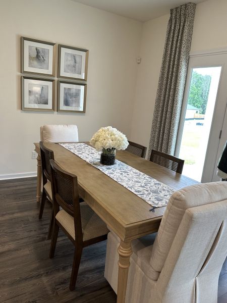 A cozy dining area with a wooden table, elegant chairs, and soft lighting complemented by framed artwork and floral decor.