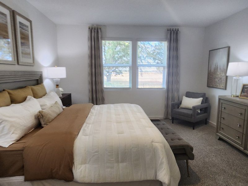 A cozy bedroom featuring a plush bed, elegant lamps, and a comfy armchair in a serene setting.