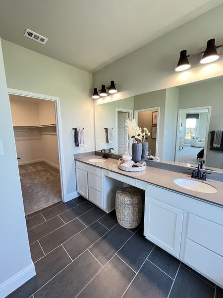 A modern bathroom featuring dual sinks, elegant lighting, and sleek gray tile flooring. A modern bathroom featuring dual sinks, elegant lighting, and sleek gray tile flooring.