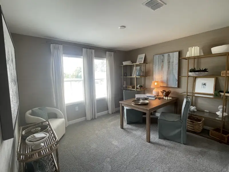 A cozy home office with a wooden desk, stylish shelving, and natural light filtering through soft drapes.
