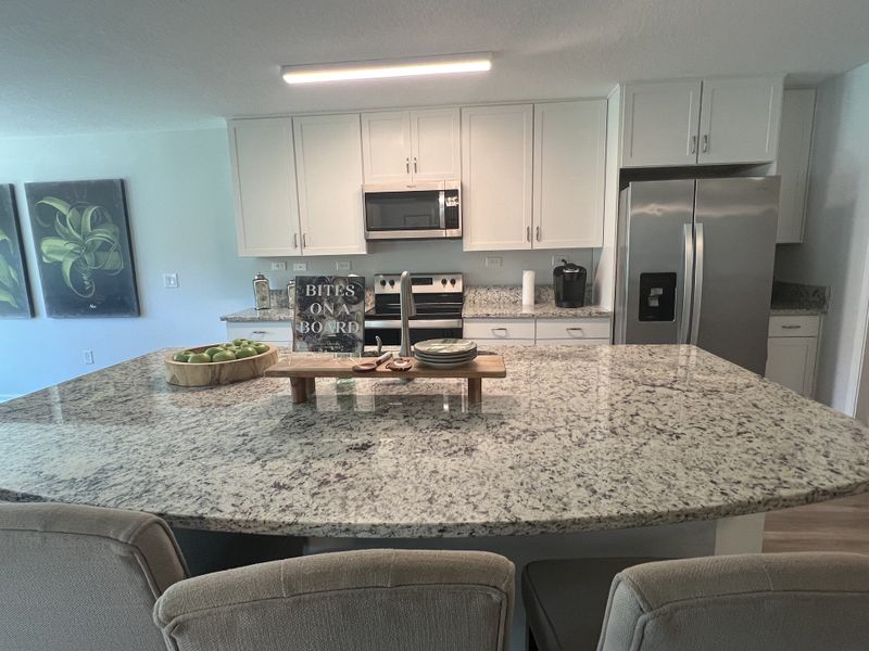 A modern kitchen featuring granite countertops, stainless steel appliances, and elegant white cabinetry. A modern kitchen featuring granite countertops, stainless steel appliances, and elegant white cabinetry.