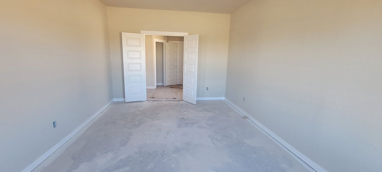 A spacious, unfinished room with double doors, neutral walls, and ample natural light.