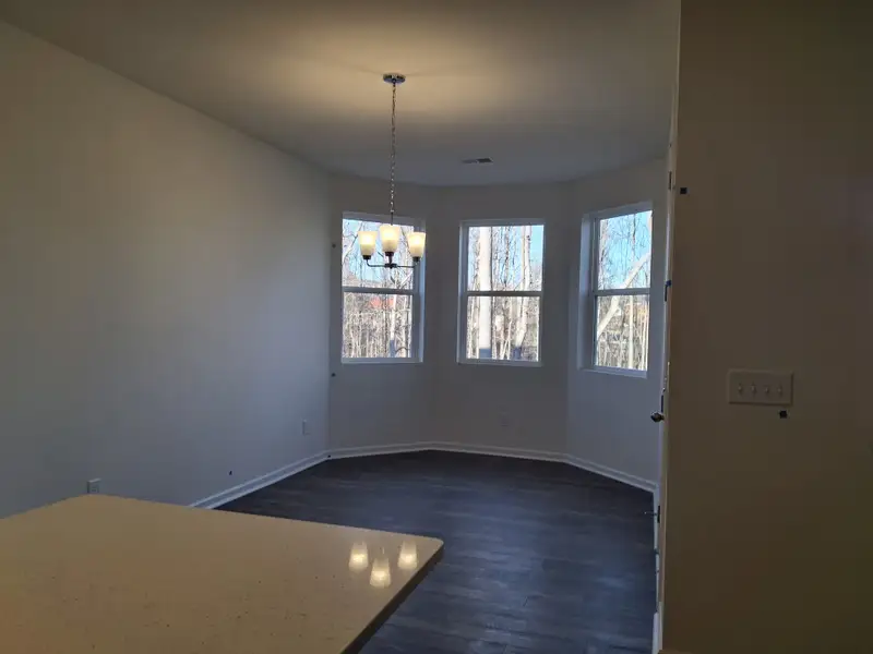 A dining area with large windows, dark wood flooring, and a modern light fixture, offering a serene view of the outdoors. A dining area with large windows, dark wood flooring, and a modern light fixture, offering a serene view of the outdoors.