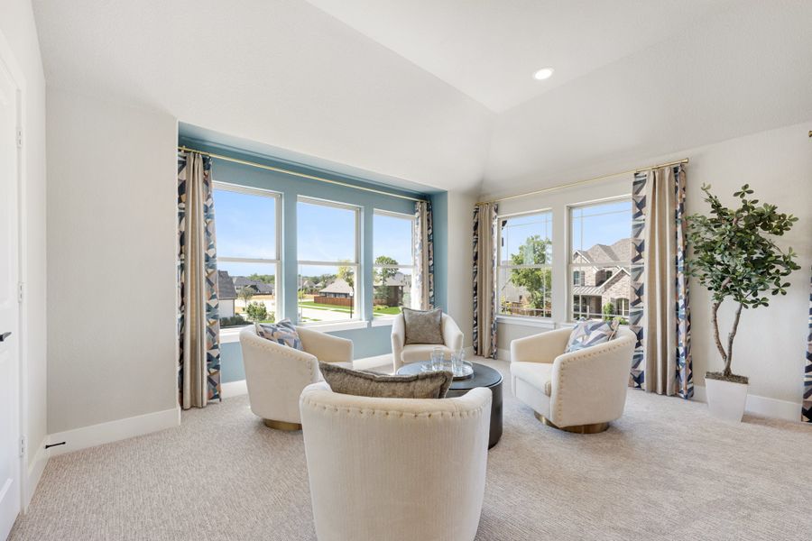 Sitting room with three white accent chairs, round coffee table, large windows, and patterned curtains on carpet flooring