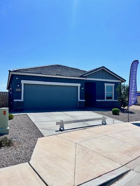 A modern blue home with a two-car garage and gravel landscaping in Amarillo Creek by Starlight Homes (Maricopa, AZ).