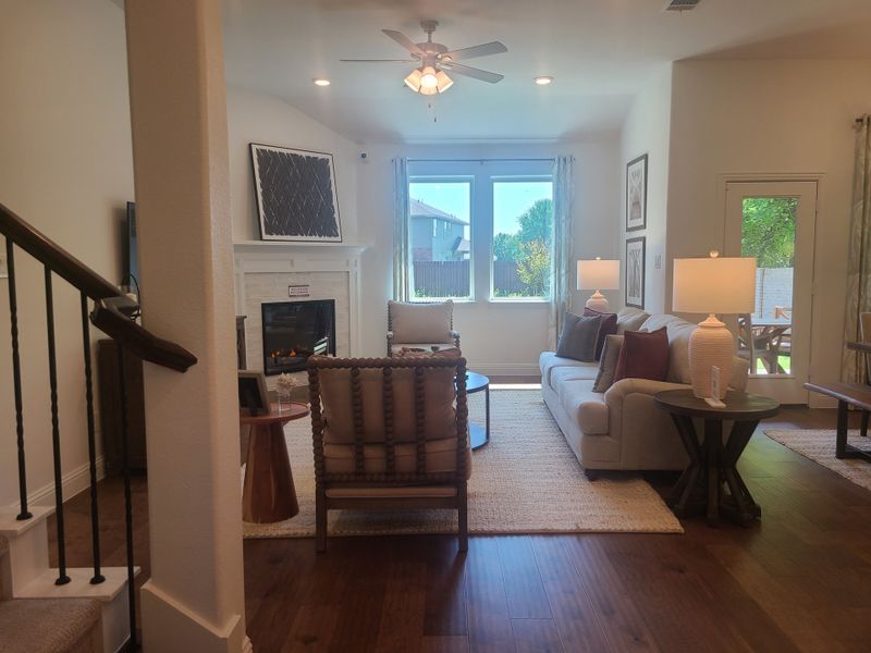 A cozy living room with a fireplace, plush seating, and natural light from large windows, offering a warm and inviting atmosphere.