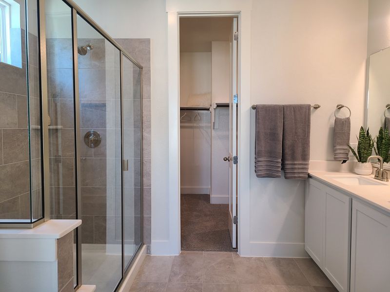 A modern bathroom featuring a glass-enclosed shower, gray tiles, and sleek vanity with fresh greenery. A modern bathroom featuring a glass-enclosed shower, gray tiles, and sleek vanity with fresh greenery.