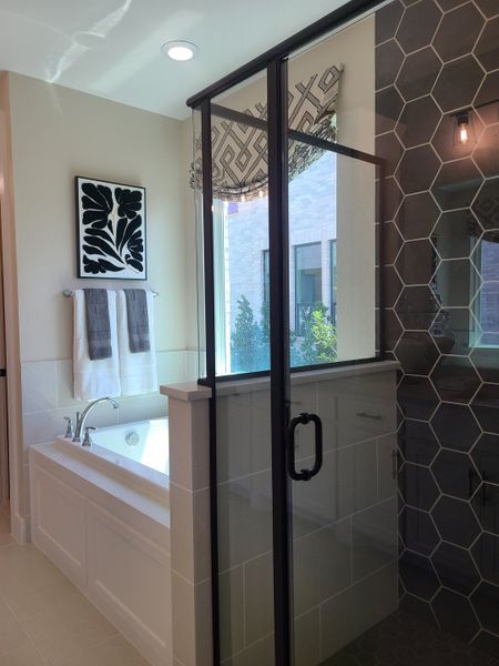 A modern bathroom featuring a soaking tub, dark hexagonal tiles, and stylish glass shower enclosure. A modern bathroom featuring a soaking tub, dark hexagonal tiles, and stylish glass shower enclosure.