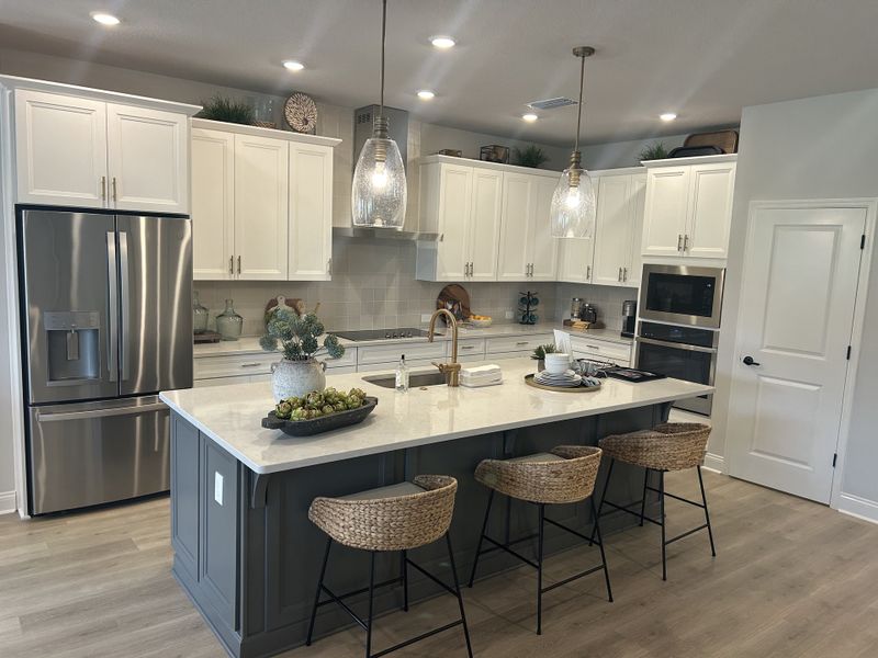 A modern kitchen with white cabinets, a large island, and pendant lighting.
