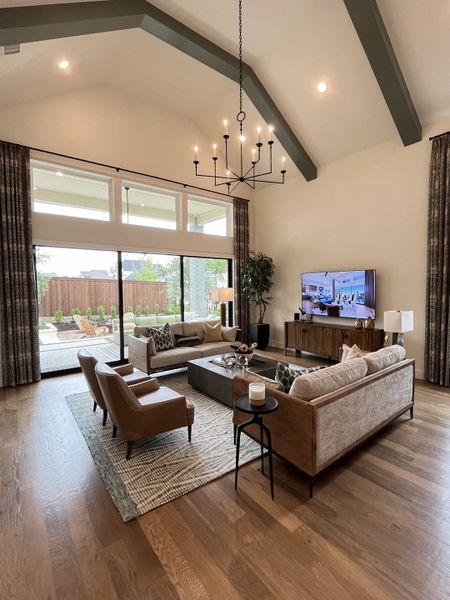 A spacious living room with vaulted ceilings, large windows, and elegant furnishings in neutral tones.