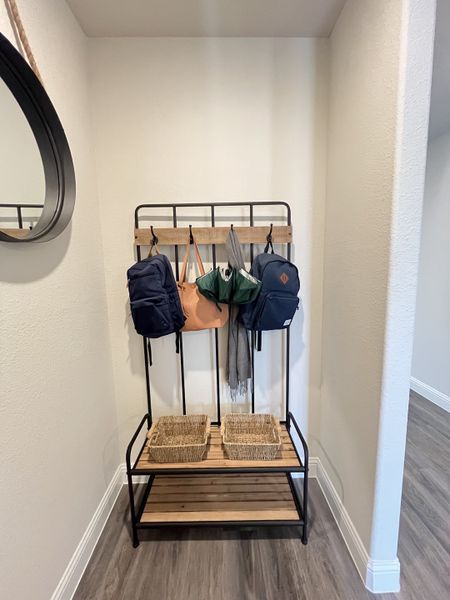 A cozy entryway with a black metal coat rack, wicker baskets, and stylish laminate flooring. A cozy entryway with a black metal coat rack, wicker baskets, and stylish laminate flooring.