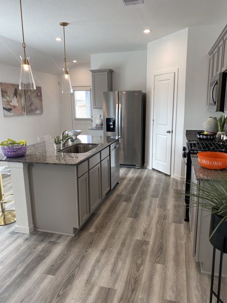 A stylish kitchen with granite countertops, stainless steel appliances, and elegant pendant lights.