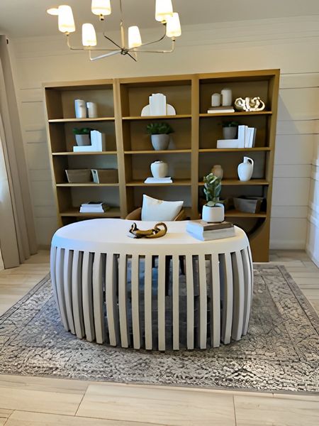 A modern study with a unique round desk, open shelving, and elegant lighting, creating a sophisticated work environment.