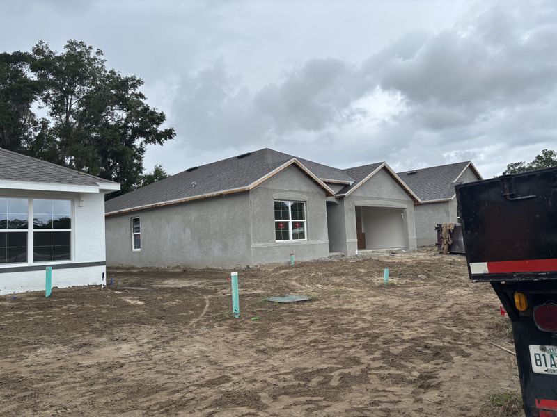 A modern grey stucco home under construction with arched windows in Autumn Glen by D.R. Horton (Belleview, FL).