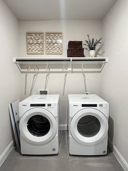 A sleek laundry room featuring modern Whirlpool appliances, minimalistic decor, and efficient shelving. A sleek laundry room featuring modern Whirlpool appliances, minimalistic decor, and efficient shelving.