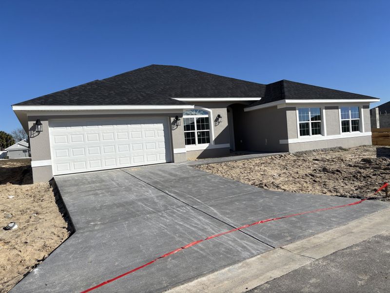 A modern ranch-style home with a spacious driveway in Brookhaven by Adams Homes (Ocala, FL).