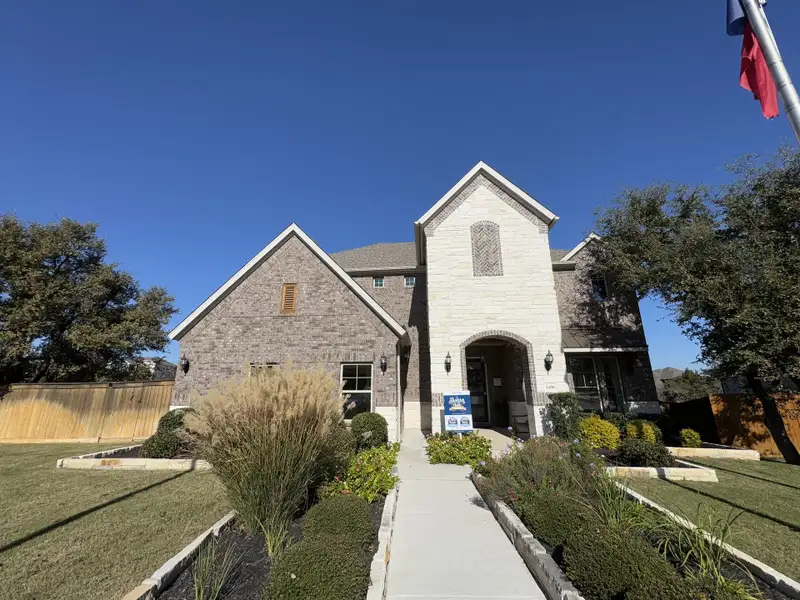 A charming stone and brick home with a landscaped yard in Deerbrooke by Brightland Homes (Leander, TX). A charming stone and brick home with a landscaped yard in Deerbrooke by Brightland Homes (Leander, TX).
