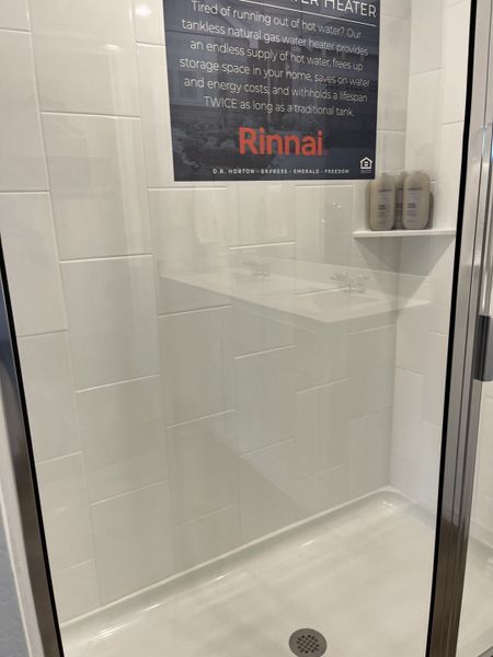 A sleek, modern shower with white tiles and a glass door, featuring convenient shelving for toiletries. A sleek, modern shower with white tiles and a glass door, featuring convenient shelving for toiletries.