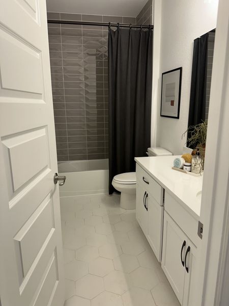 A sleek bathroom with a modern design, featuring hexagonal floor tiles, a white vanity, and gray tiled shower. A sleek bathroom with a modern design, featuring hexagonal floor tiles, a white vanity, and gray tiled shower.