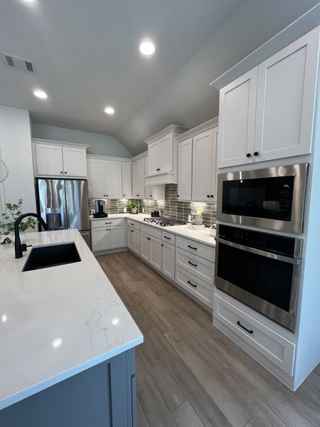 A modern kitchen featuring sleek white cabinetry, a spacious island, and stainless steel appliances.