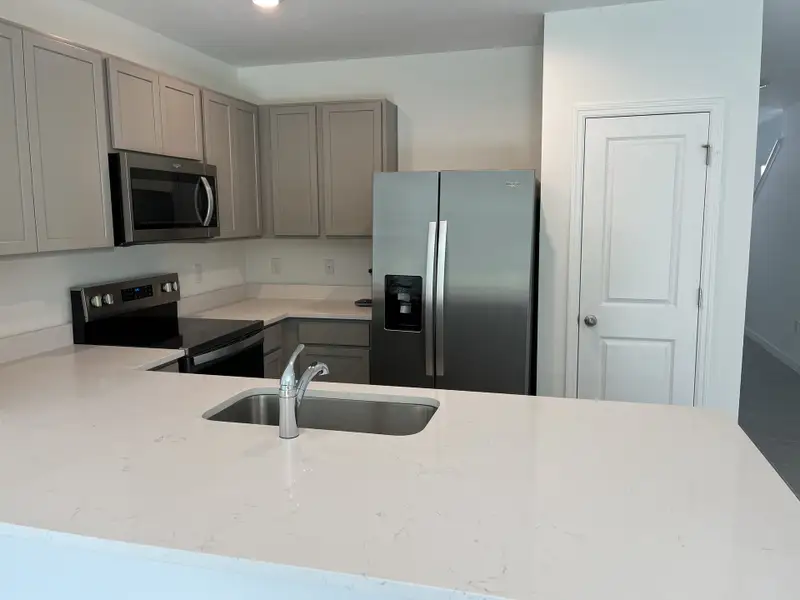 A modern kitchen with sleek white countertops, stainless steel appliances, and light gray cabinetry for a contemporary look.