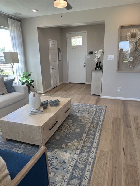 A cozy living room with wood flooring, a patterned rug, and stylish decor featuring neutral tones and modern art.