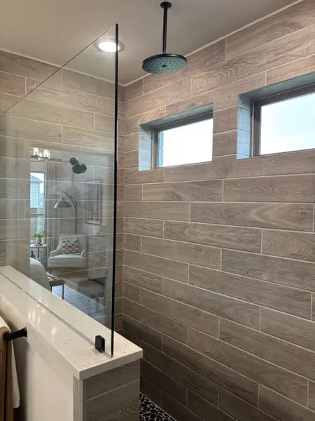 A modern shower with wood-look tiles, a glass partition, and sleek fixtures.