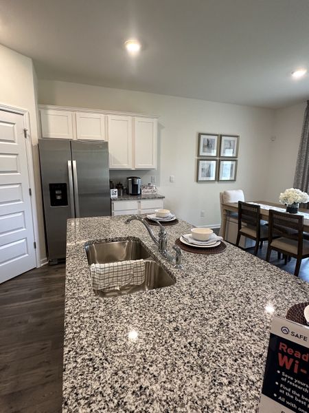 A modern kitchen with granite countertops, stainless steel appliances, and a dining area with elegant wall art.