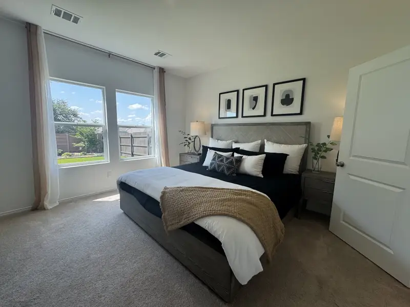 A cozy bedroom with large windows, plush bedding, abstract art, and neutral tones creating a serene retreat.