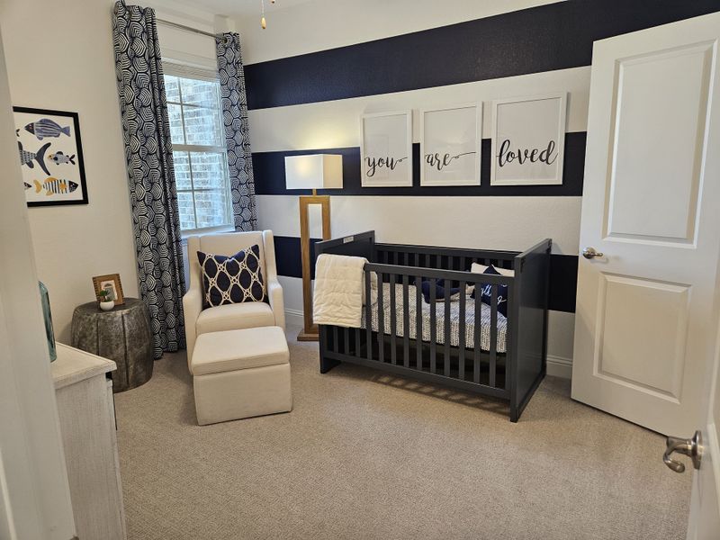 A cozy nursery features bold striped walls, a comfortable armchair, and a sleek dark crib, creating a serene atmosphere.