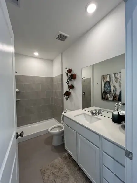 A sleek bathroom with a modern vanity, wall-mounted planters, and gray tile accents.