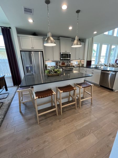 A stylish kitchen with stainless steel appliances, pendant lighting, and a spacious island with wooden stools.