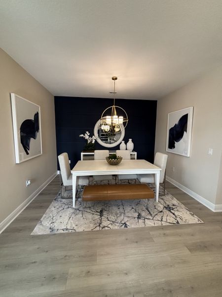 A sophisticated home office featuring a deep navy accent wall, sleek modern furniture, and stylish decor, offering a functional yet aesthetically pleasing workspace in Crossroads at Kelly Park by Dream Finders Homes (Apopka, FL).