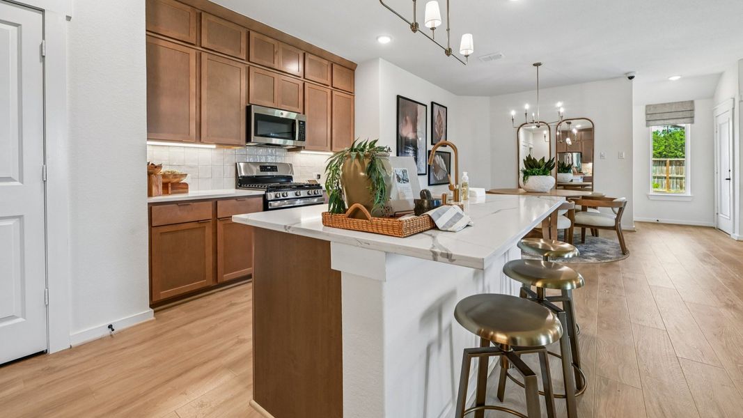Elegantly designed kitchen featuring light wood cabinetry, sleek gold fixtures, and premium appliances in Cielo.