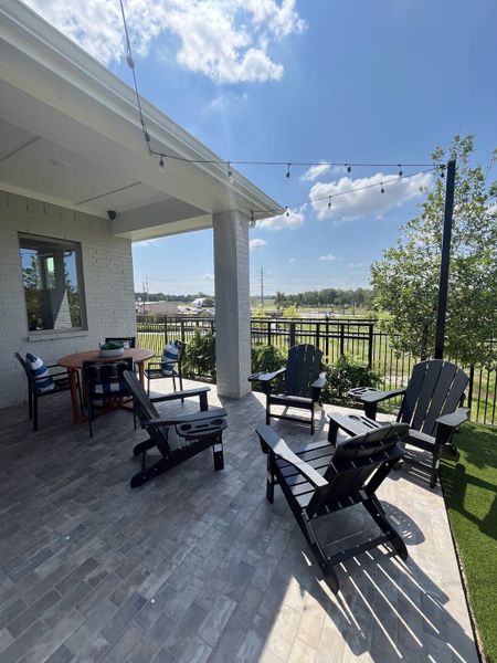 A cozy patio with Adirondack chairs, string lights, and a round table, perfect for outdoor relaxation and gatherings. A cozy patio with Adirondack chairs, string lights, and a round table, perfect for outdoor relaxation and gatherings.