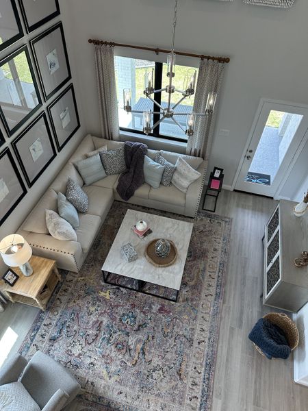 A modern living room with a plush sectional sofa, chic chandelier, and a vibrant patterned rug, creating an inviting atmosphere. A modern living room with a plush sectional sofa, chic chandelier, and a vibrant patterned rug, creating an inviting atmosphere.