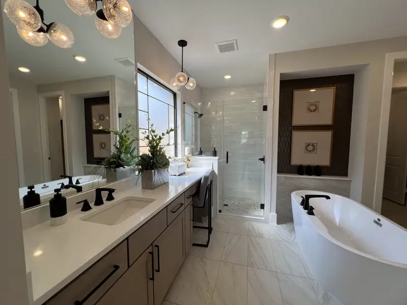 A luxurious bathroom featuring a sleek freestanding tub, elegant vanity, and glass-enclosed shower with modern lighting.