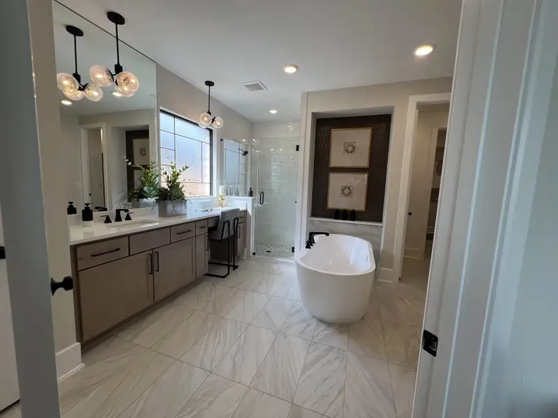A luxurious bathroom featuring a freestanding tub, dual sinks, and elegant lighting with polished finishes.