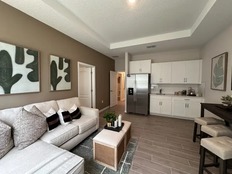 A cozy living space with a white sofa, modern art, and a sleek kitchen featuring stainless steel appliances.