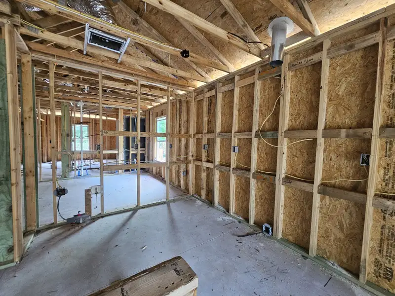A home under construction featuring exposed wooden framing and wiring, showcasing the development stage of the property.