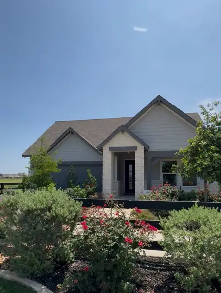 Charming gray home with a floral garden in Estancia Ranch - Classic Series by Meritage Homes (San Antonio, TX).
