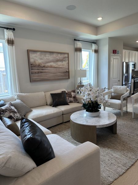 A cozy living room with a plush sectional, elegant artwork, and a chic marble-topped coffee table amidst soft natural lighting. A cozy living room with a plush sectional, elegant artwork, and a chic marble-topped coffee table amidst soft natural lighting.