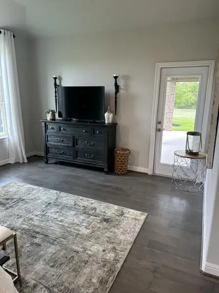 A cozy living area with a sleek entertainment console, rustic accents, and a stylish rug on dark hardwood floors. A cozy living area with a sleek entertainment console, rustic accents, and a stylish rug on dark hardwood floors.