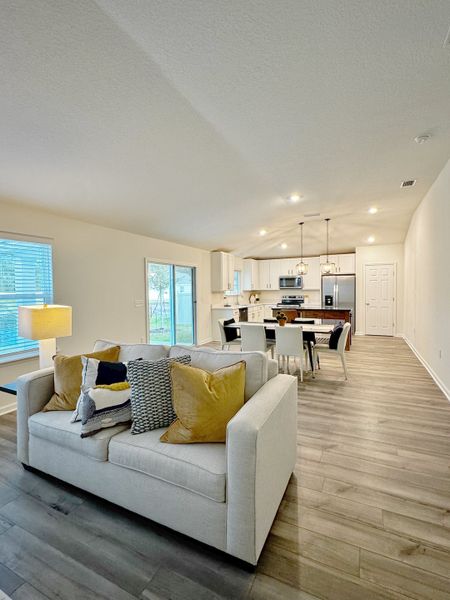 An inviting open-concept living area featuring a cozy sofa, stylish dining space, and modern kitchen with pendant lighting.