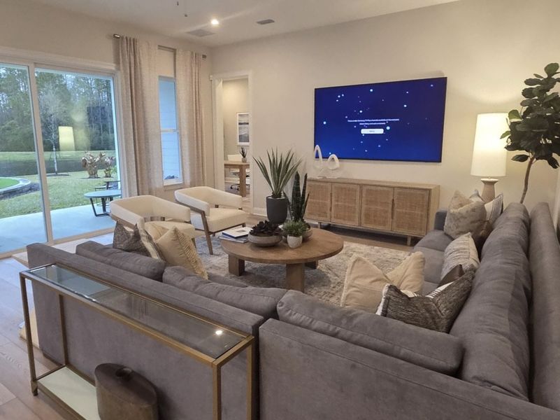 A cozy living room with a spacious sectional, modern TV, and patio view, featuring warm lighting and elegant decor. A cozy living room with a spacious sectional, modern TV, and patio view, featuring warm lighting and elegant decor.