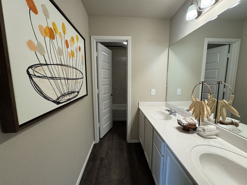 A modern bathroom featuring dual sinks, a large mirror, abstract art, and sleek countertops.