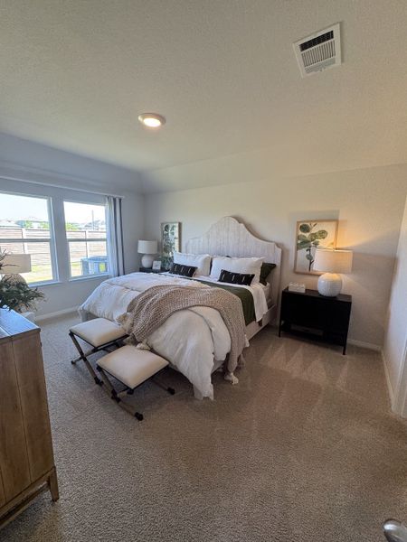 A cozy bedroom with a plush bed, soft lighting, and elegant decor in a serene, carpeted setting.