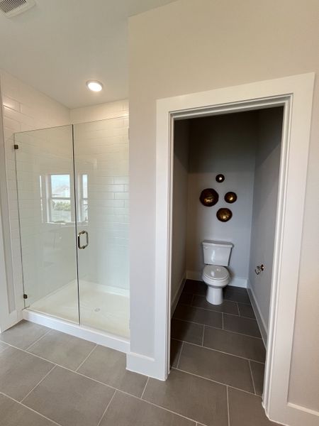 A sleek bathroom with a glass-enclosed shower, modern toilet, and elegant wall decor.