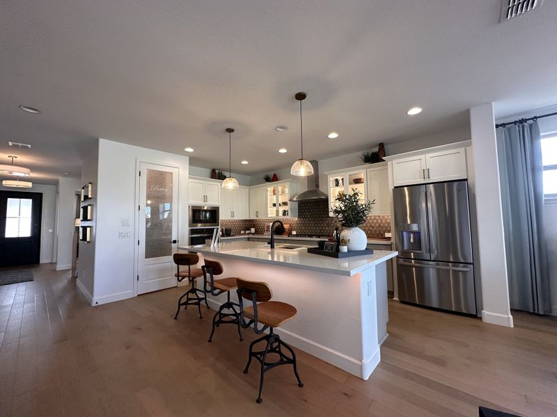 A modern kitchen with sleek white cabinets, stainless appliances, and a spacious island featuring chic pendant lighting.