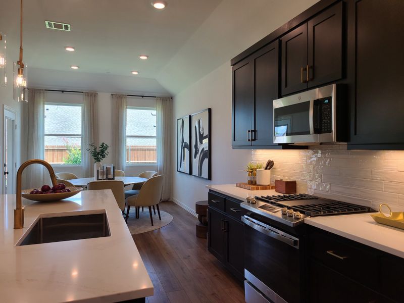 A modern kitchen features sleek black cabinets, stainless appliances, and an elegant dining area with natural light. A modern kitchen features sleek black cabinets, stainless appliances, and an elegant dining area with natural light.